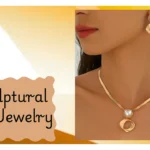 A digital collage highlighting a bold, architectural jewelry set. A model wears a sleek gold herringbone snake necklace with a pearl and twisted geometric square pendant, paired with matching statement earrings. A wavy, warm beige text box on the left reads "Sculptural Gold Jewelry."